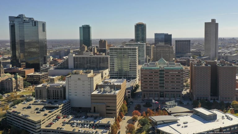 Aerial view of downtown city skyline with multiple high-rise buildings and urban development under clear sky